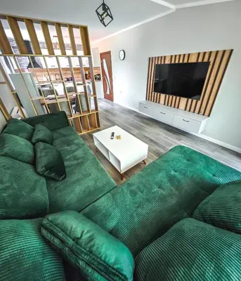 a living room with a green couch and a television at Апартамент Петя 2 in Velingrad