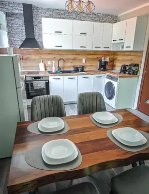 a kitchen with a wooden table with white plates on it at Апартамент Петя 2 in Velingrad