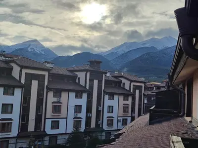 a group of buildings with mountains in the background at 3 Rooms Apartment next to the Ski lift in Bansko