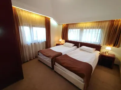 a hotel room with two beds and two windows at 3 Rooms Apartment next to the Ski lift in Bansko