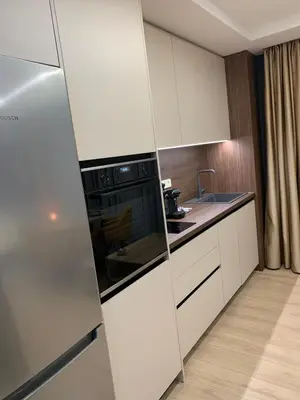 a kitchen with white cabinets and a refrigerator at The Modern Nest Apartment with FREE Underground Parking in Plovdiv