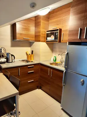 a kitchen with wooden cabinets and a stainless steel refrigerator at Апартамент в Белведере Холидей клуб in Bansko
