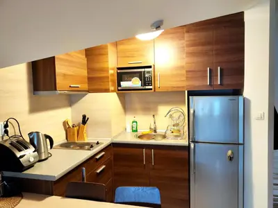 a kitchen with wooden cabinets and a refrigerator at Апартамент в Белведере Холидей клуб in Bansko