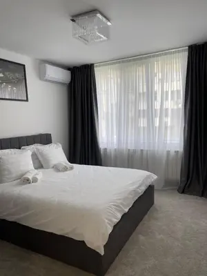 a bedroom with a bed with white sheets and a window at Апартамент Кashmir in Smolyan