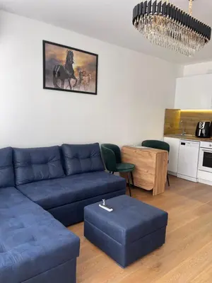 a living room with a blue couch and a kitchen at Апартамент Кashmir in Smolyan