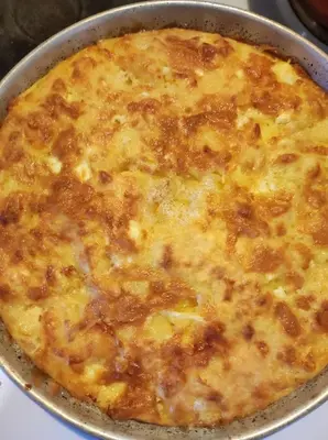 a cheese pizza in a pan on a stove at Кулинарна къща за гости СОФРИЦА in Hvoyna
