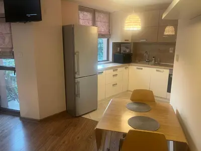 a kitchen with a refrigerator and a wooden table at Guest House Amaya Happy in Plovdiv