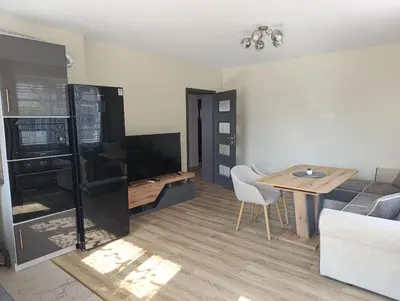 a living room with a table and a television at Самостоятелен Apartment Emili in Sapareva Banya