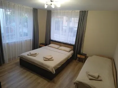 a bedroom with two beds and two windows at Самостоятелен Apartment Emili in Sapareva Banya
