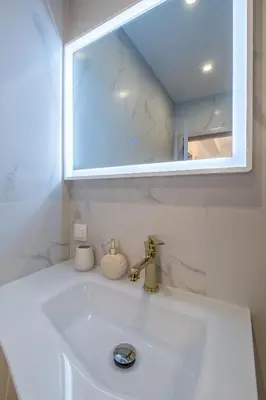 a white bathroom sink with a mirror and a sink at Elegant Deluxe 2 Bedroom apartment in Sofia