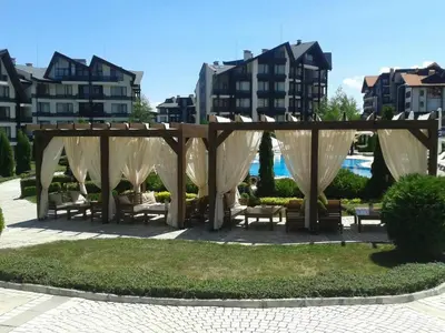 a gazebo with benches in a park with buildings at Mountain view apartment in Aspen Golf Resort with SPA in Bansko
