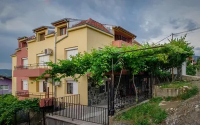 a yellow house with a fence in front of it at Guest House JoJi in Sapareva Banya