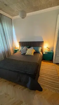 a bedroom with a bed with two lamps and a rug at Кокетно Кътче in Sofia