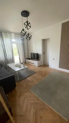 a living room with wooden floors and a large room at Кокетно Кътче in Sofia
