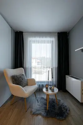 a living room with a chair and a table and a window at Планинска вила АЛТЕА in Mostowo