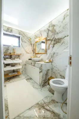 a marble bathroom with a toilet and a mirror at Планинска вила АЛТЕА in Mostowo
