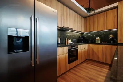 a stainless steel refrigerator in a kitchen with wooden cabinets at Hypnotic Thermal Villas with private SPA in Banya