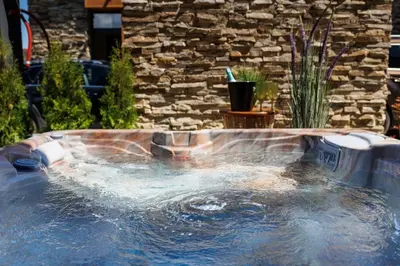 a hot tub in a backyard with a stone wall at Hypnotic Thermal Villas with private SPA in Banya