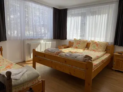 a bedroom with two beds and two windows at Къща за гости Хриси in Mala Tsŭrkva