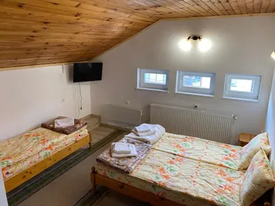 a bedroom with two beds and a flat screen tv at Къща за гости Хриси in Mala Tsŭrkva