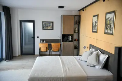 a bedroom with a bed and a kitchen with orange chairs at Villa Alveare in Banya