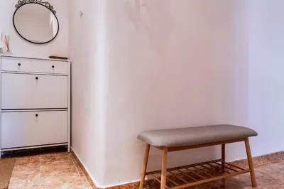 a stool in front of a white wall with a mirror at Teo's Cozy Top Central Apartment in Sofia