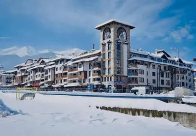 a large building with a clock tower in the snow at Spacious Studio - Bansko Royal Towers in Bansko