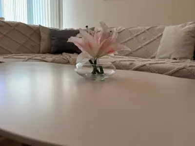 a glass vase with a pink flower on a table at Апартамент в сърцето на ПЛОВДИВ in Plovdiv