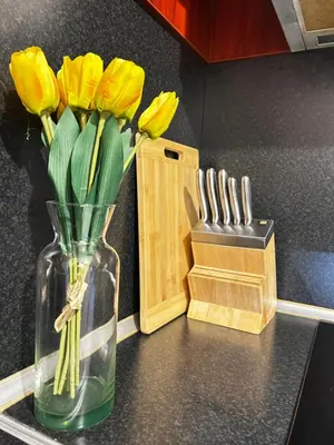 a vase filled with yellow flowers on a counter with a knife block at Rea Flora - Cozy Stay With Free Parking in Sofia