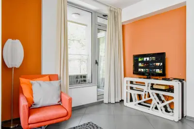 an orange living room with an orange chair and a tv at Joy Apartment - Stylish 2BD in Oborishte by Flat Mаnager in Sofia