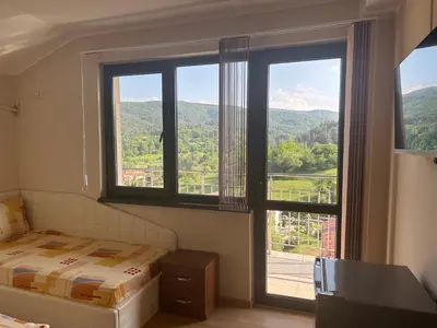a bedroom with a bed and a large window at Къща за гости Sunrise - Батак in Batak