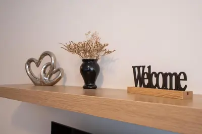 a wooden shelf with a vase and a welcome sign at Belvedere Bansko - Cozy 1BR - Ski in Winter, Swim in Summer! by Flat Mаnаger in Bansko