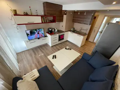 a living room with a blue couch and a kitchen at Premium Nomad's Suite-Near Subway-Terrace in Sofia