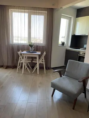 a living room with a table and a chair at Premium High Rise, Gorgeous City Views in Plovdiv