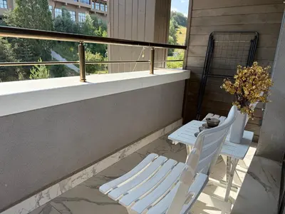 a balcony with two white chairs and a table at Nikol5 Deluxe in Velingrad