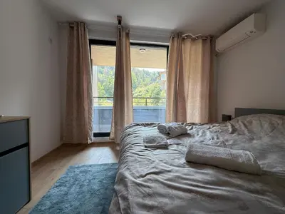 a bedroom with a bed and a large window at Nikol5 Deluxe in Velingrad
