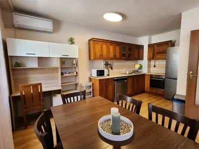 a kitchen and dining room with a wooden table at Trinity Apartment & Pool with Spa Near Center in Bansko