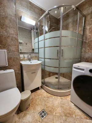 a bathroom with a shower and a toilet and a sink at Trinity Apartment & Pool with Spa Near Center in Bansko