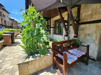 a bed under an umbrella on a patio at Trinity Apartment & Pool with Spa Near Center in Bansko