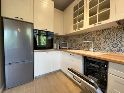 a kitchen with white cabinets and a stainless steel refrigerator at Park Apartment in Sofia