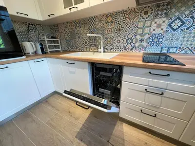 a kitchen with white cabinets and a wooden counter top at Park Apartment in Sofia