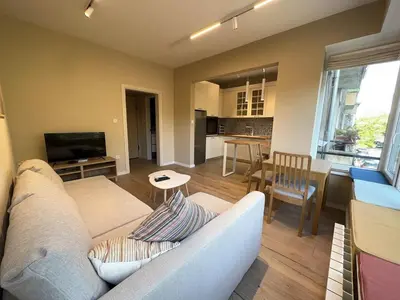 a living room with a white couch and a kitchen at Park Apartment in Sofia
