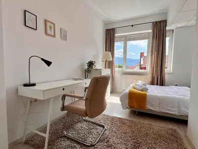 a bedroom with a desk and a bed with a window at Central 53 Vitosha View 2BD Apartment in Sofia