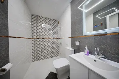 a white bathroom with a toilet and a sink at Brand New Vitosha View Apartment - Free Parking - Metro Access in Sofia