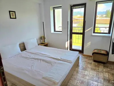 a white bed in a room with two windows at Стаи за гости ЖиВел in Oreshak