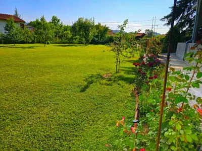 a garden with a green lawn with a tree and flowers at Стаи за гости ЖиВел in Oreshak