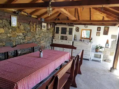 a dining room with a table and a stone wall at Стаи за гости ЖиВел in Oreshak