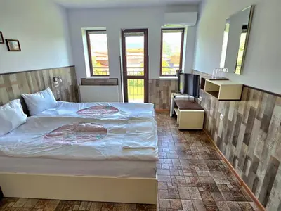 a bedroom with a large bed and a television at Стаи за гости ЖиВел in Oreshak