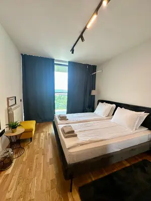a bedroom with a large bed with blue curtains at The Skyline Residence Sofia in Sofia