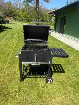 a barbecue grill sitting on the grass in a yard at Villa Green House in Tscherweni Breg